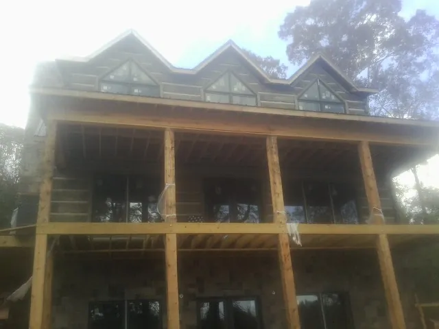 Dormers and porch framing on a large log home under construction — Roof Coating work by our crew in Rudolph