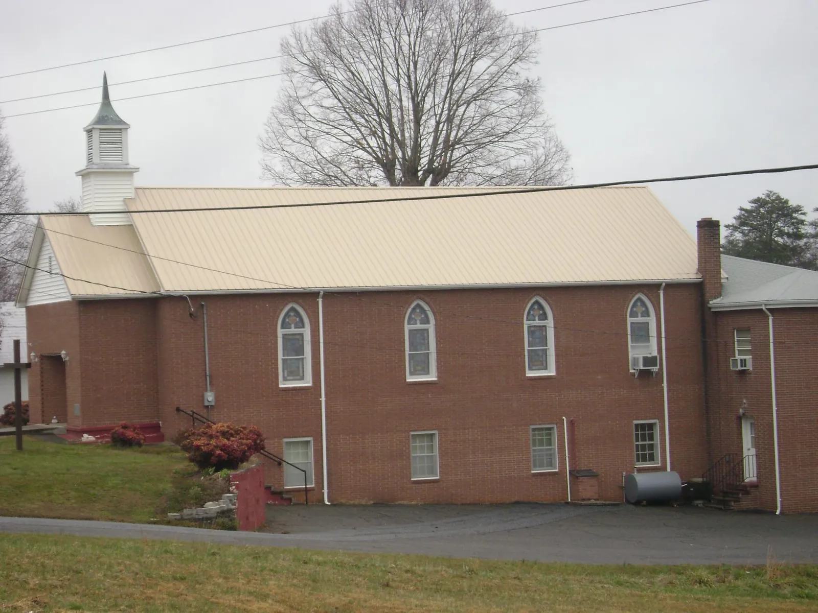 New tan metal roof on a brick church with a white steeple in Rudolph