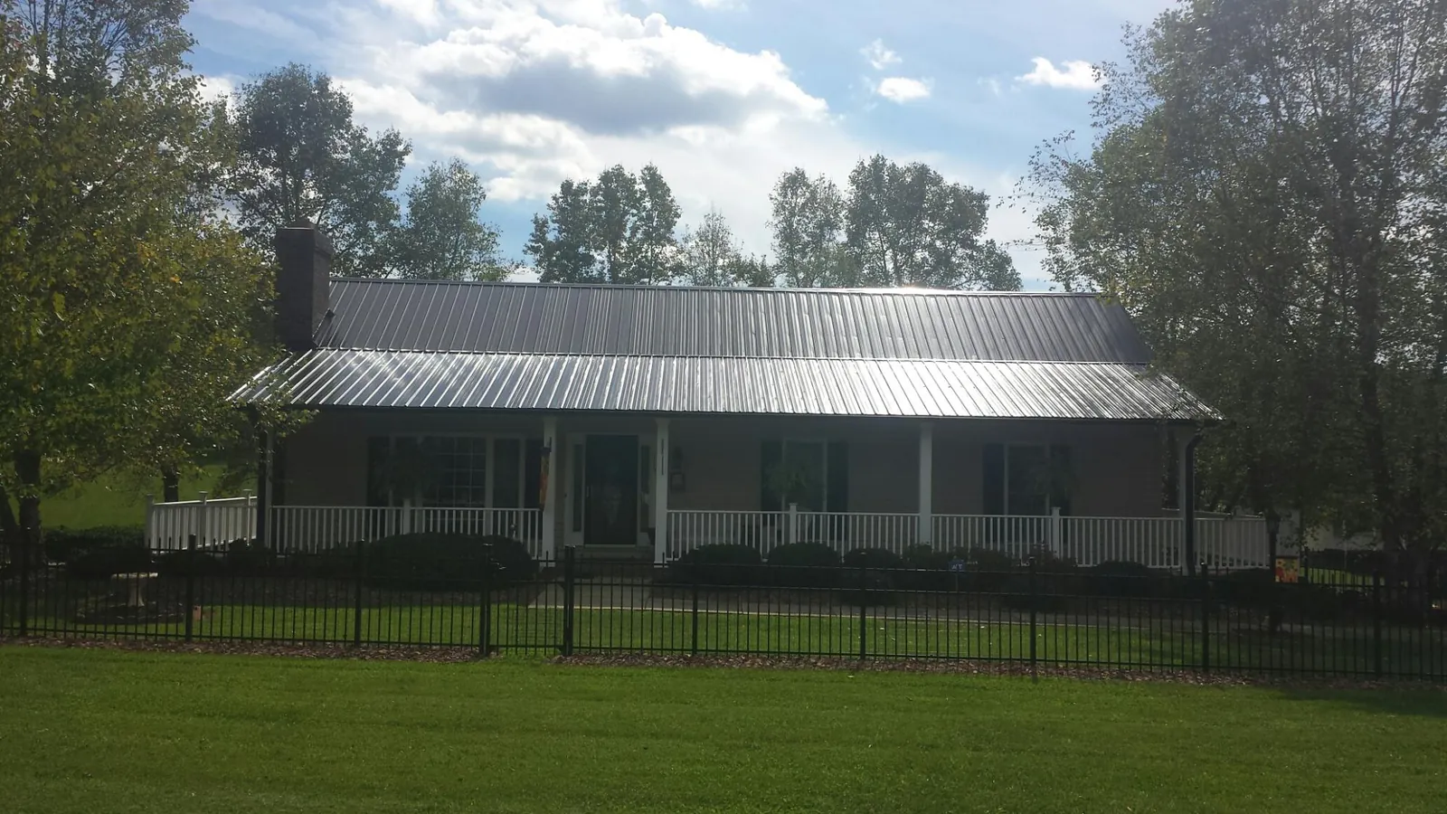 Gray metal roof on a brick ranch with a full width front porch — Gutter Guard Installation work by our crew in Rudolph